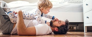 Male playing with son on hardwood floor